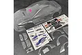 An unpainted clear polycarbonate RC car body shell for the Bittydesign Kanjo-S, including decal sheets, plastic accessories, and an instruction manual.