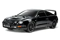 A studio shot of a black Tamiya Toyota Celica GT-Four RC car on a white background, showing the detailed body, wheels, and rear spoiler.