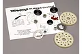 Traxxas slipper clutch set components including two spur gears, metal washers, nuts, and small red friction pads arranged on an instruction sheet.