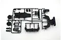 A black plastic parts tree for a Tamiya RC model containing various chassis components like shock towers and skid plates.