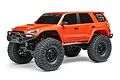 An orange Axial SCX24 Toyota 4Runner RC rock crawler viewed from a front three-quarter angle on a white background.