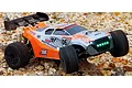 UDI Entelodon 1/18 scale RC buggy with orange and silver bodywork driving over rocky terrain with illuminated LED headlights.