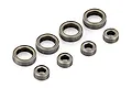 A set of eight metal shielded ball bearings of two different sizes arranged on a white background.