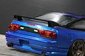 Rear view of a blue 1/10 scale RC Nissan 180SX drift car body featuring a black rear wing mounted on the trunk.