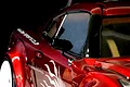 Close-up of a black side mirror mounted on a metallic red RC car body shell.