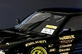 A close-up of a black RC car body shell featuring a black windscreen wiper blade installed on the front windshield.