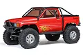 A red Axial SCX10 III 1987 Toyota SR5 RC rock crawler truck with a black roll cage and off-road tires, shown against a white background.
