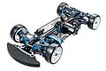 A high-angle studio shot of a Tamiya TRF421X 1/10 scale 4WD RC touring car chassis, featuring blue anodized aluminum parts and carbon fiber components.