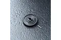 A black MST 50T spur gear with a small metal pin resting on a textured dark grey surface.
