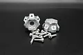 Two silver aluminium wheel hex hubs with a DOT design and a set of matching metal socket head screws on a black background.