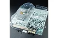 An unpainted clear polycarbonate RC car body shell for a Toyota GR86, including decals, plastic parts, and hardware on a dark surface.