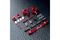 A set of red anodized aluminium RC rear hubs and associated hardware including turnbuckles, ball ends, and spacers on a dark textured surface.