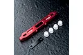 MST red anodized aluminium lower suspension arm mount with white plastic inserts and a black metal plate on a dark textured surface.