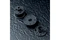 Three black plastic RC gearbox components arranged on a textured dark grey surface.