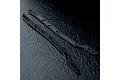 Two black MST RC chassis upper deck rails laid diagonally on a dark textured surface.