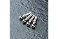 Four silver-colored metal ball studs arranged in a row on a dark, textured surface.