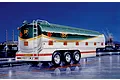 Illustration of a BP heavy fuel tank trailer parked on a wet road at night with a refinery in the background.