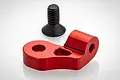A red anodized aluminium engine mount component for an RC car, accompanied by a single black countersunk machine screw.