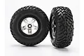Two Traxxas 2.2/3.0 inch off-road tires pre-mounted on satin chrome and black wheels against a white background.