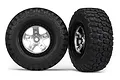 Two Traxxas 2.2/3.0 inch off-road tyres mounted on satin chrome and black wheels, shown from front and side angles.