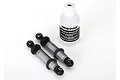 Two silver Traxxas GTS shock absorbers with black plastic ends and a bottle of Traxxas silicone shock oil on a white background.