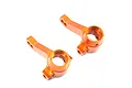 A pair of orange anodized aluminium front steering hubs for an HPI RS4 RC car, shown from a high angle against a white background.