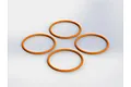Four orange rubber O-rings arranged in a diamond pattern on a plain white background.