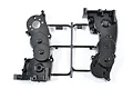 A black plastic Tamiya gear box case set on a sprue tree against a white background.