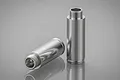 Two silver aluminium RC shock absorber bodies with threaded ends, displayed on a reflective grey surface.
