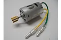 A silver RS-380 brushed RC motor with a brass pinion gear attached to the shaft and green and yellow wires with bullet connectors.