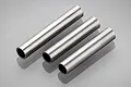 Three cylindrical metal tube spacers arranged diagonally on a light grey reflective surface.