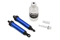 Two blue anodized aluminum Traxxas GTR shock absorbers with a bottle of silicone shock oil and small plastic parts on a white background.