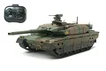 A Tamiya 1/35 scale JGSDF Type 10 RC tank model in camouflage paint, shown with its matching black 2.4GHz remote controller against a white background.