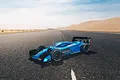 An ARRMA Limitless 1/7 scale RC car with a matte blue body shell parked on an asphalt road in a desert landscape.
