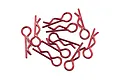 A collection of ten red metal R-clips or body pins for RC cars scattered on a white background.