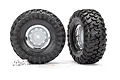 Two Traxxas 1.9 inch Canyon Trail crawler tires pre-mounted on chrome rims, with two small wheel hex hubs included in the foreground.