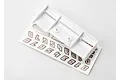 A white plastic RC car wing for a Traxxas 1/16 E-Revo resting on top of a decal sheet featuring numbers.