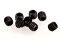 A cluster of seven small black metal grub screws with hexagonal drive sockets, isolated against a white background.