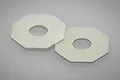 Two off-white octagonal slipper clutch pads for RC vehicles, shown on a reflective grey surface.