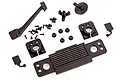 A collection of black plastic RC car body accessories including a grille, mirrors, mounts, and various small screws on a white background.