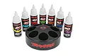 A set of seven Traxxas shock oil bottles in various weights arranged behind a black circular spinning carousel storage rack on a white background.