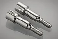 Two silver metal rear wheel axles for a BlackZon 1/12 scale RC car, shown side by side on a reflective surface.