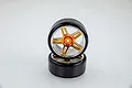 Two RC drift wheels with smooth black tires and five-spoke gold and chrome rims stacked on a white background.