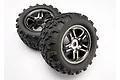 Two Traxxas 3.8 inch Maxx monster truck wheels with black chrome rims and aggressive tread rubber tyres, set against a plain white background.