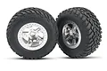 Two Traxxas RC off-road tires pre-mounted on satin chrome wheels, featuring a deep tread pattern and beadlock-style rim detail.