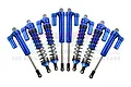 A set of eight blue anodized aluminium piggyback shock absorbers for an RC car arranged in a fan shape against a white background.