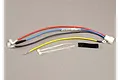 Traxxas EZ-Start wiring harness kit including multi-coloured wires, connectors, zip ties, and a piece of adhesive foam tape on a grey surface.