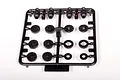 A black plastic parts tree containing various shock piston and spacer components for Axial RC vehicles.