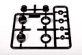 A black plastic parts tree containing various shock absorber components for an RC vehicle, including caps, collars, and spacers.