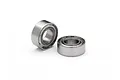 Two small metal shielded ball bearings sitting on a white surface.